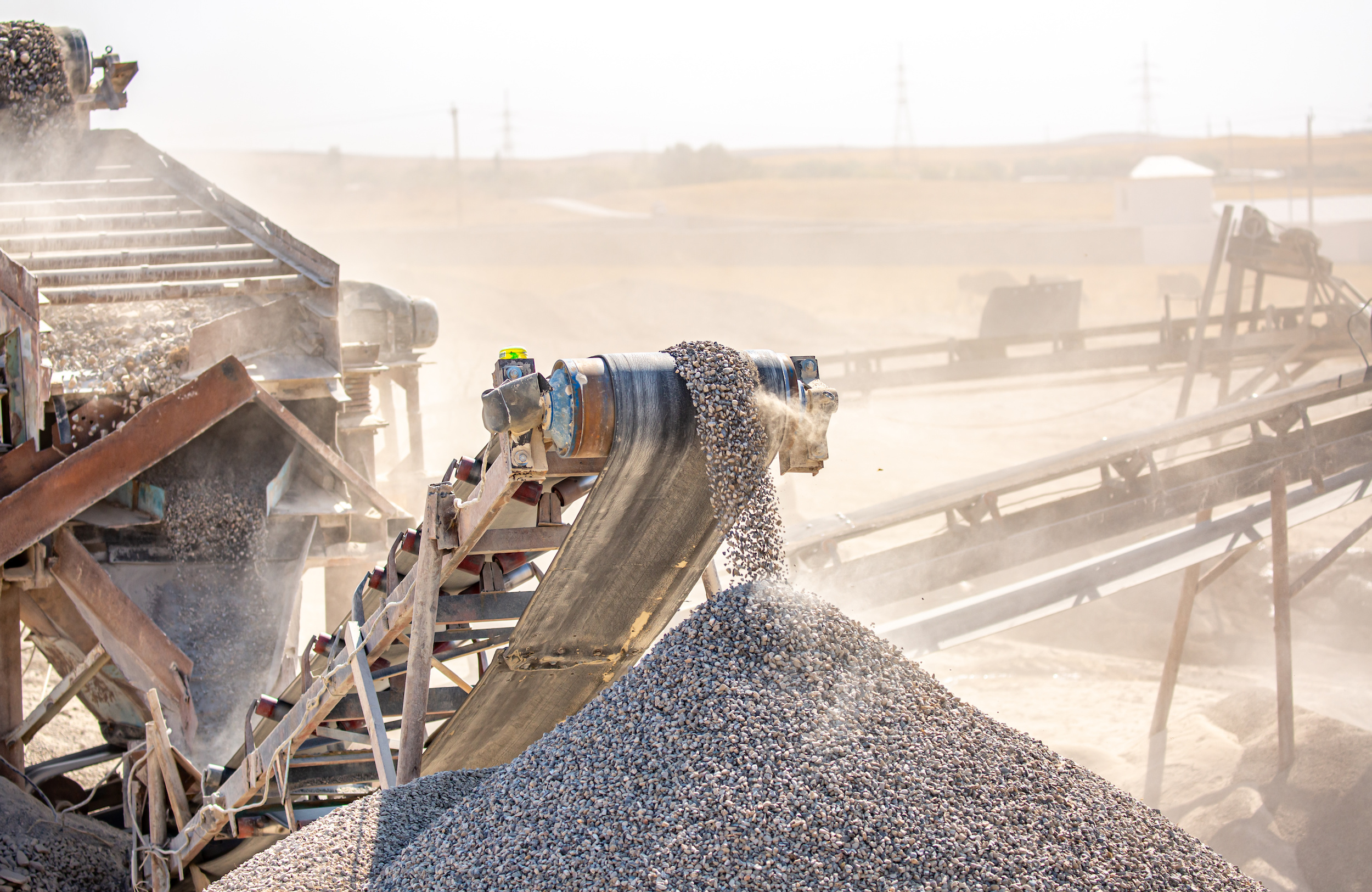 Vibrating screen stone crusher in operation. Crushing stones in a quarry for processing minerals, cement, limestone. Heavy and mobile equipment in a quarry for processing stone into building material. Waste Valorization - CORE Environmental Consulting